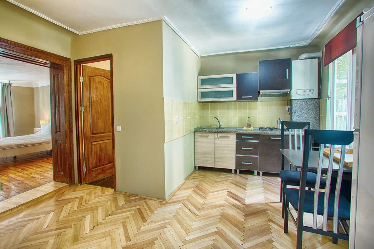 The studio's own kitchen, with dark blue units, a sink, a hob, and a table with chairs.