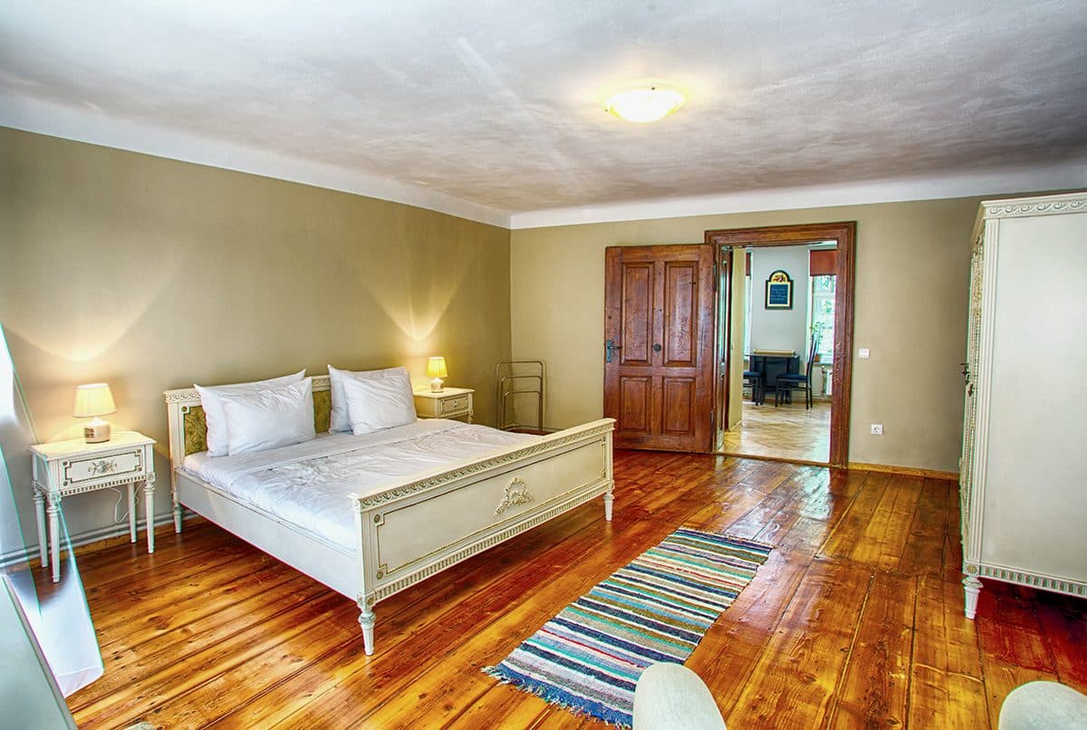 The studio's bedroom, with a wooden double bed, bedside tables and a woven runner on the parquet.