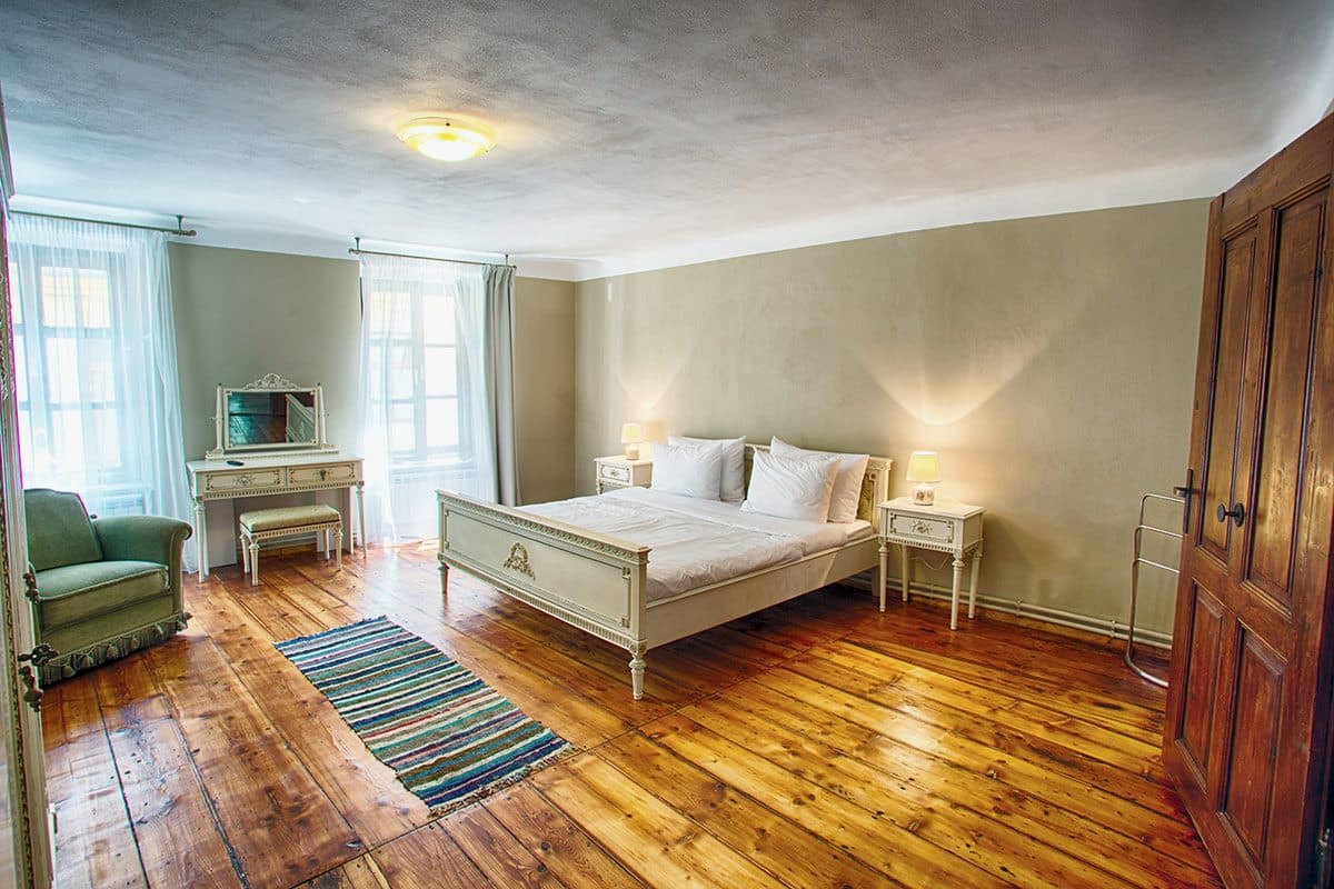The studio's bedroom seen from the living area, with the bed and the wooden double doors.